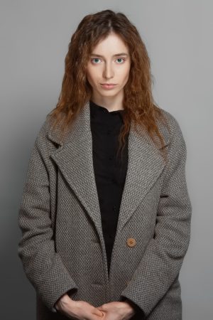 woman in houndstooth overcoat posing against gray 2026 03 17 00 01 12 utc